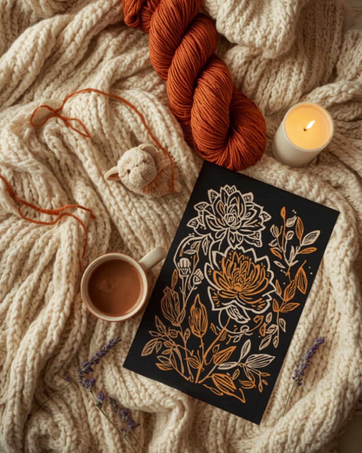 Cozy evening flat-lay with terracotta yarn, a small crochet critter, a botanical poster, cocoa, a candle, and lavender on a cream knit blanket